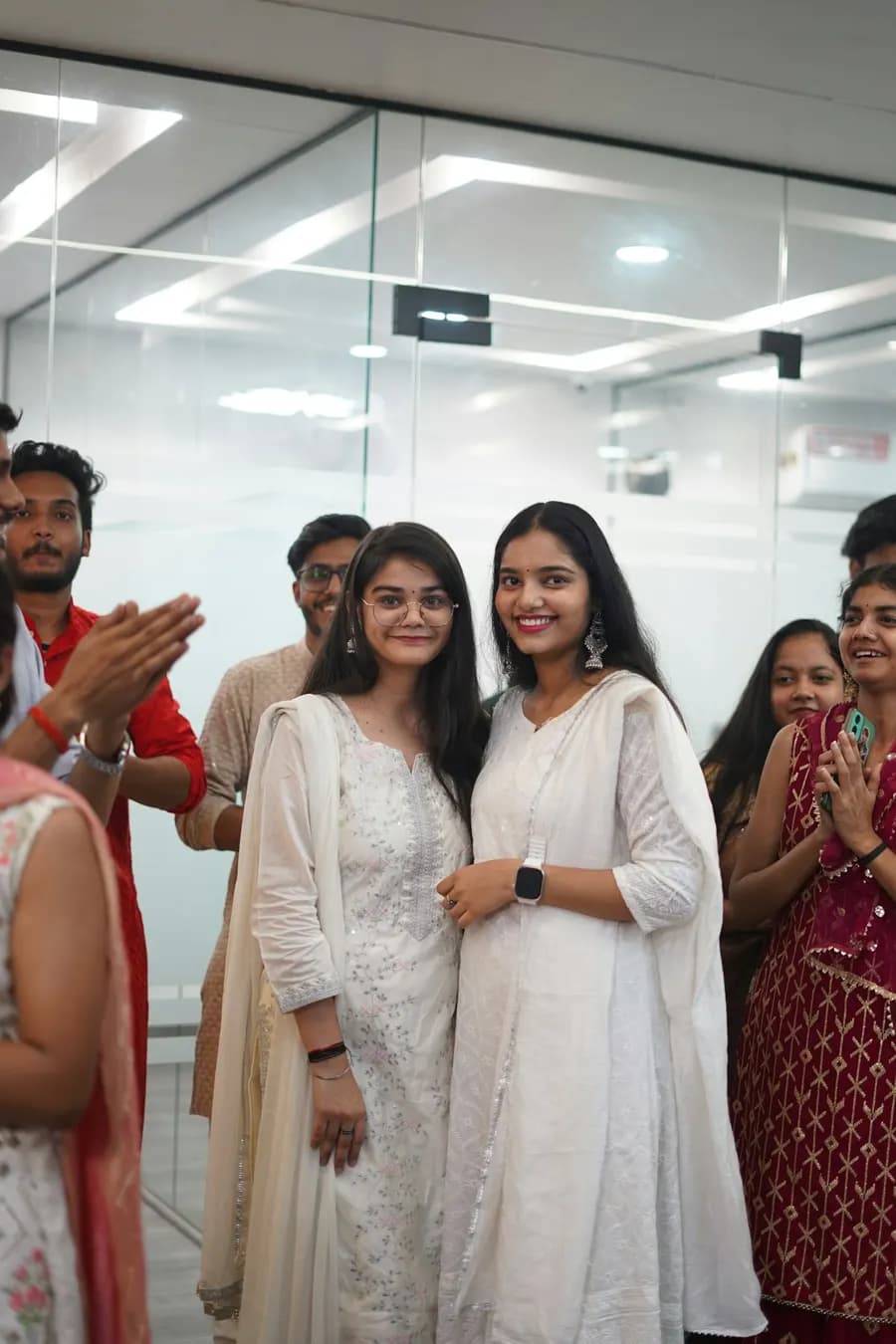 Two women smiling as colleagues applaud them