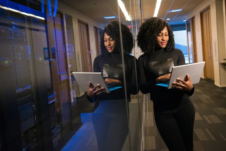 Two women professionals walking through an office with laptops