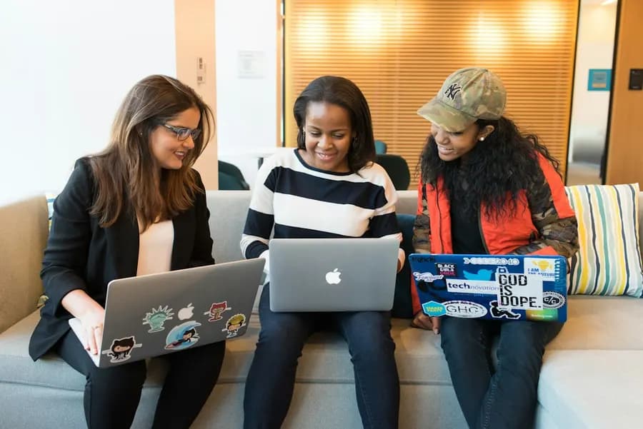 Three women collaborating on laptops