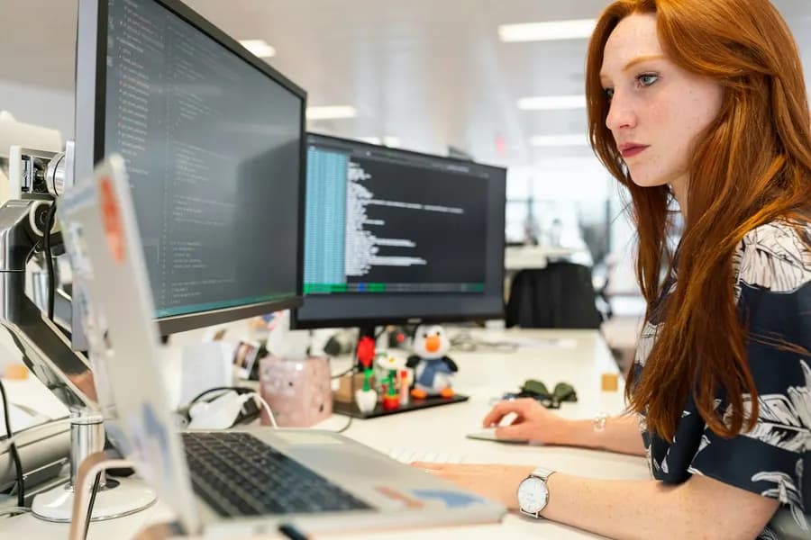 A woman working across multiple monitors in an office