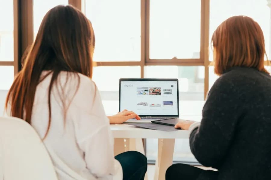 Two women discussing work on a laptop